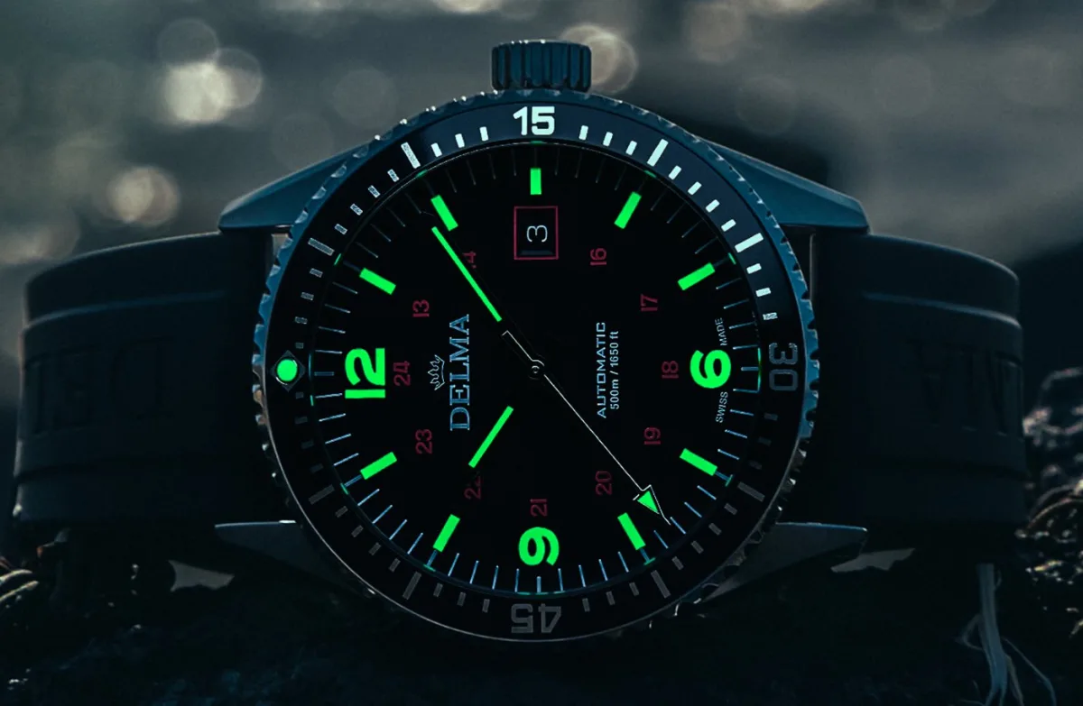Delma Cayman Field Watch with black aluminum bezel and tapered lugs.